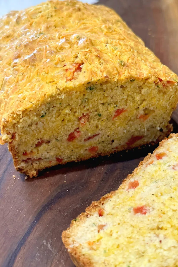 loaf of tomato basil quick bread sliced on cutting board